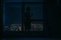 Silhouette of a young woman on the panoramic window background with the glass of vine in her hand and is looking on the night city Royalty Free Stock Photo