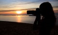 Silhouette young woman photographer taking picture on the beach ,sunset scene Royalty Free Stock Photo