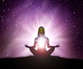 Silhouette of young woman practices yoga and meditates on top of the mountain with night sky, star