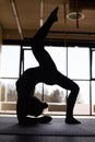 Silhouette of a young woman practicing the concept of yoga, performing a handstand, against the background of panoramic Windows Royalty Free Stock Photo