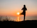 Silhouette young woman practicing yoga on the beach above sea at amazing sunset. fitness, sport, yoga and healthy Royalty Free Stock Photo