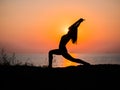 Silhouette young woman practicing yoga on the beach above sea at amazing sunset. fitness, sport, yoga and healthy Royalty Free Stock Photo