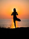 Silhouette young woman practicing yoga on the beach above sea at amazing sunset. fitness, sport, yoga and healthy Royalty Free Stock Photo