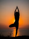 Silhouette young woman practicing yoga on the beach above sea at amazing sunset. fitness, sport, yoga and healthy Royalty Free Stock Photo