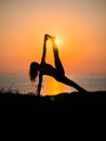 Silhouette young woman practicing yoga on the beach above sea at amazing sunset. fitness, sport, yoga and healthy Royalty Free Stock Photo