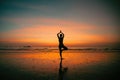 Silhouette young woman practicing yoga on the beach at amazing sunset. Royalty Free Stock Photo