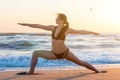 Silhouette of a young woman practicing yoga on the beach at sunrise. Sport, wellness concept Royalty Free Stock Photo