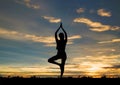 Silhouette young woman practicing yoga on the beach in sunset. Royalty Free Stock Photo