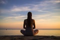 Silhouette of young woman practicing yoga at sunrise on the beach, rear view of a women yoga exercise and pose for a healthy life Royalty Free Stock Photo