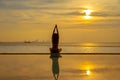 Silhouette young woman practicing yoga on swimming pool and the beach at sunset Royalty Free Stock Photo