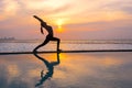 Silhouette young woman practicing yoga on swimming pool and the beach at sunset. Royalty Free Stock Photo