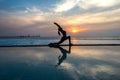 Silhouette young woman practicing yoga on swimming pool and the beach at sunset Royalty Free Stock Photo