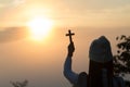 Silhouette of young woman praying with a cross at sunrise, Christian Religion concept background Royalty Free Stock Photo