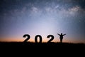 Silhouette of young woman raising hands prepare to welcome the new year 2022 and looking view night sky, star and milky way alone