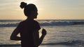 Silhouette of young woman running on sea beach at sunset. Girl jogging along ocean shore during sunrise. Female Royalty Free Stock Photo