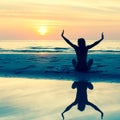 Silhouette of a young woman sitting on the beach during a beautiful sunset Royalty Free Stock Photo