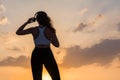 Silhouette young woman in the sport clothes, headphones listen music on the sunset sky backgrounds. The concept of healthy Royalty Free Stock Photo