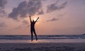 Silhouette of a young woman in sportswear jumping on the seashore at sunset or dawn Royalty Free Stock Photo