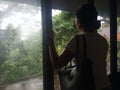 Silhouette of young woman standing alone looking out from the window glass.