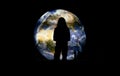 Silhouette of young woman standing in front of large inflatable model of planet Earth glowing at night, view form behind Royalty Free Stock Photo