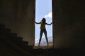 Silhouette of a young woman standing in the window opening destroyed an abandoned building