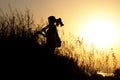 Silhouette of a young woman traveling in the throwing shoulder on professional photographic tripod