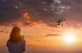 Silhouette of young woman using drone at sunset for photos and video making - Happy woman having fun with new technology trends in Royalty Free Stock Photo