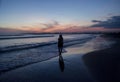 Silhouette of a young woman walking on the beach during sunset time