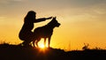 Silhouette young woman walking with a dog in the field at sunset, a girl in an autumn jacket on hill showing her pet in the Royalty Free Stock Photo