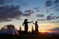 Silhouette of young woman and child giving each other high five near camping at dawn on top of mountain Royalty Free Stock Photo