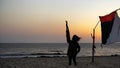Silhouette of youth holding up a palestinian flag near Gaza beach. Gaza - Palestine