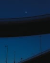 Silhouetted bridge against a backdrop of an evening sky with a crescent moon.