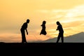 Silhouetted children rope skipping in sunset
