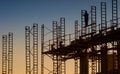 A silhouetted construction worker standing on metal scaffolding