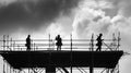 Silhouetted Construction Workers on Unfinished Building Against Cloudy Sky in Black and White Royalty Free Stock Photo