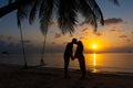 Silhouetted couple in love kisses on the beach during sunset