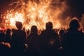 Silhouetted crowd watching a fiery golden fireworks display on a festive night