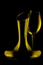 Silhouetted elegant curved crystal wine decanter and glass on dark background