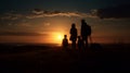 Silhouetted family watches the sun disappear below the horizon