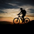 Silhouetted figure with mountain bike against dramatic sunset backdrop