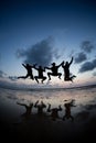 Silhouetted friends jumping in sunset at beach