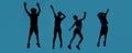 Silhouetted full length shot of four little sportive kids looking joyful while posing, jumping isolated over blue