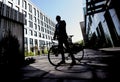 Silhouetted full length shot of mature businessman looking away while standing with his bicycle near modern office