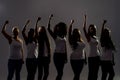 Silhouetted group of diverse women raised their arms, fists while standing over grey background. Diversity, womens