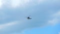 Silhouetted helicopter flying high and far away in an expressive blue cloudy weather sky