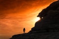 Silhouetted hiker walks into burning sky sunset