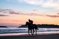 A silhouetted horse rider galloping across a beach at sunrise Royalty Free Stock Photo