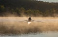 Silhouetted Man Rowing Single Scull on Foggy Water at Sunrise