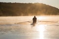 Silhouetted Man Rowing Single Scull on Foggy Water at Sunrise