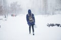 Abstract blurred people silhouettes walking along snowy street in winter. Heavy snowfall in the city. Blurred image of a man